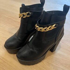 Black boots with high heels and gold chain accent.